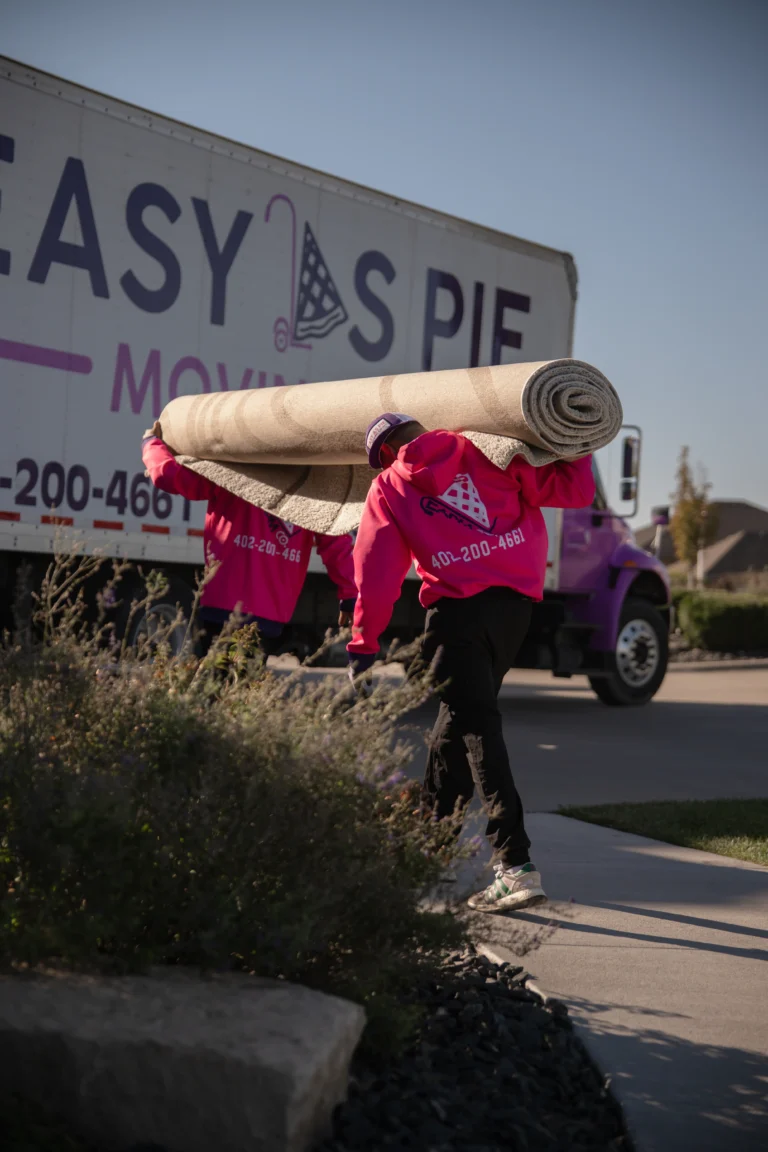 Easy as Pie Omaha movers carrying a large rolled carpet from the truck during a residential move. military movers Omaha
