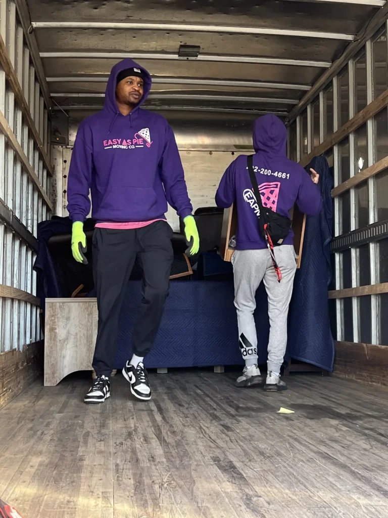 Two Easy As Pie movers standing inside a padded moving truck