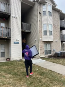 Easy As Pie mover carrying a TV out of an Omaha apartment building
