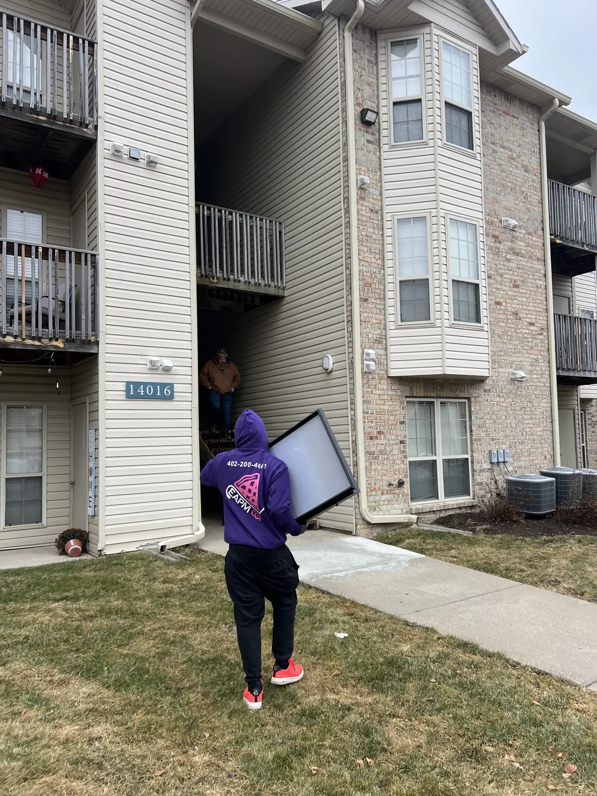 Easy As Pie mover carrying a TV out of an Omaha apartment building