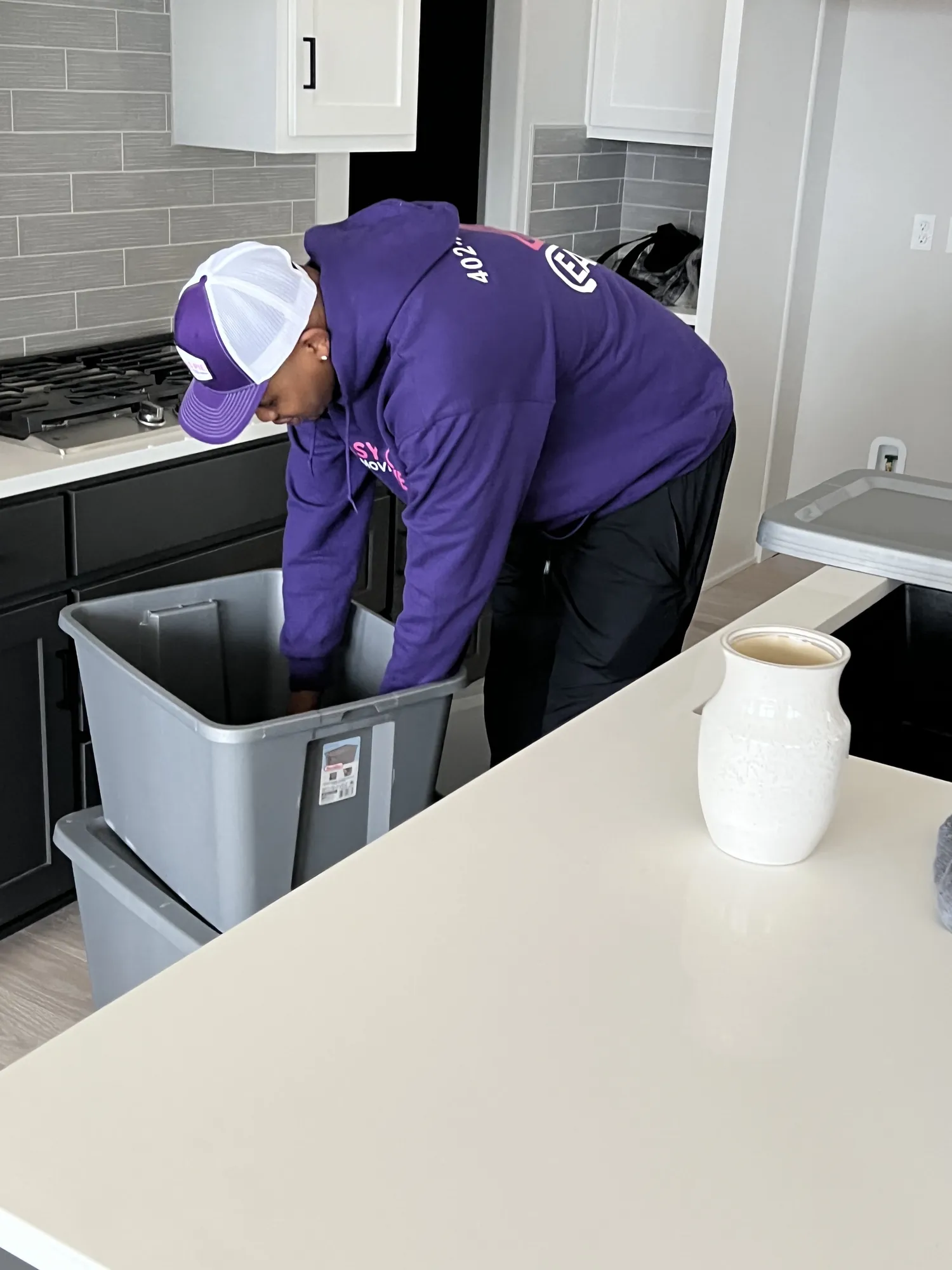Easy As Pie mover packing kitchen items into a reusable plastic moving bin
