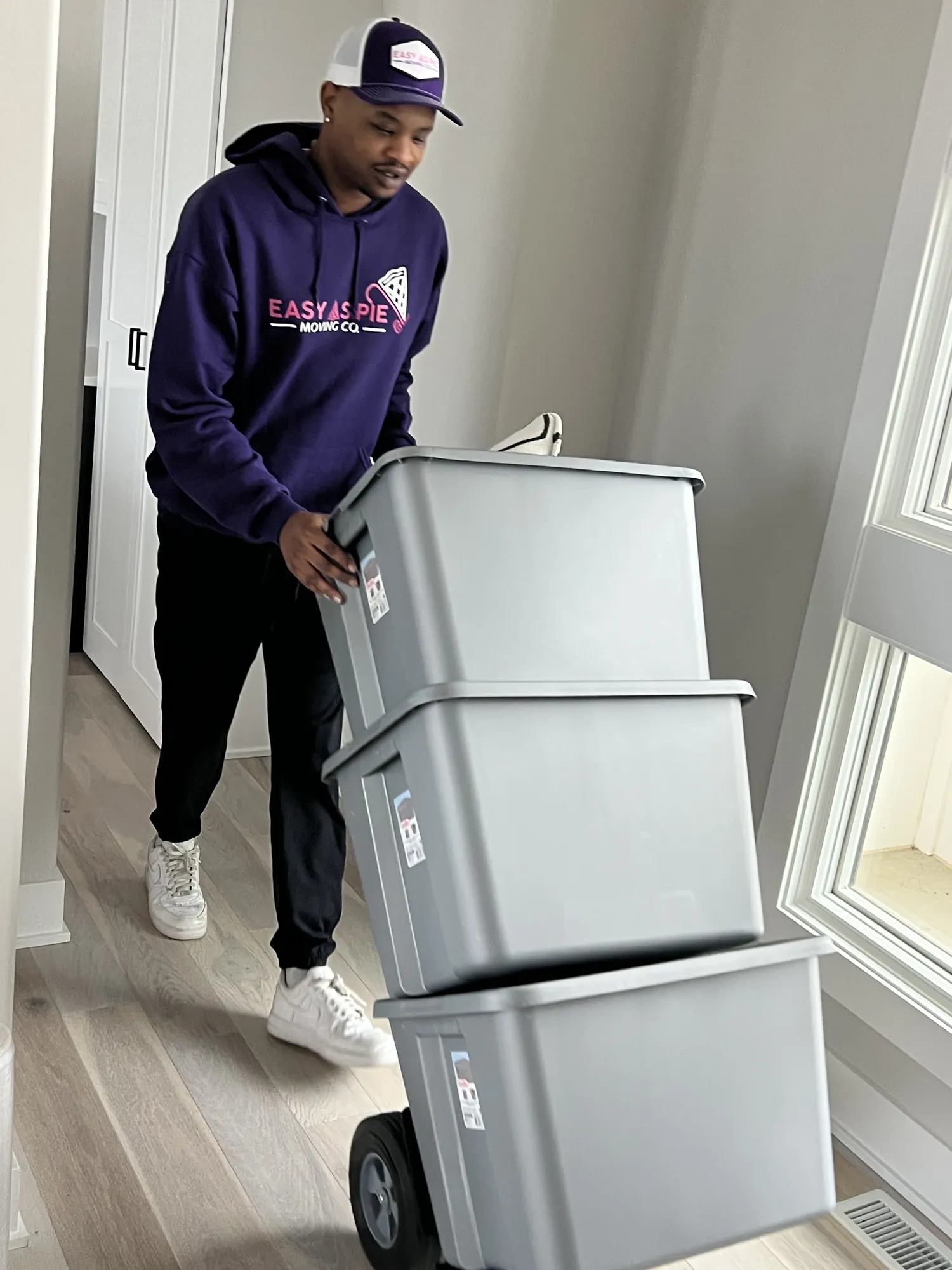 Easy As Pie mover wheeling stacked plastic moving bins on a dolly