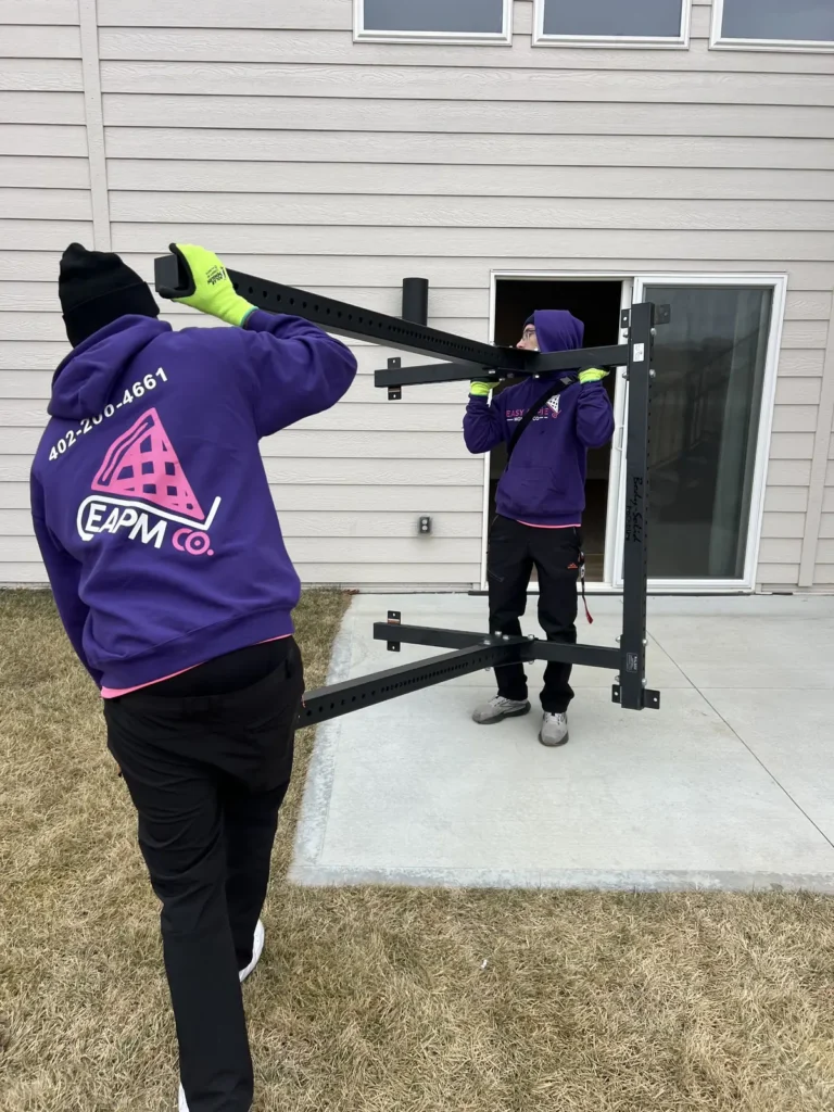 Easy As Pie movers in hats and gloves carrying a wall-mounted rack on a cold day