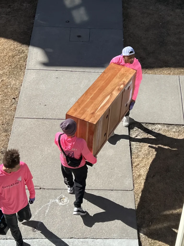 Easy As Pie movers carrying a wooden dresser down a sidewalk