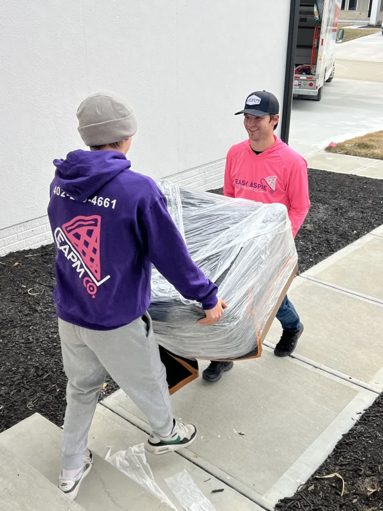 Easy As Pie movers carrying plastic-wrapped furniture outside