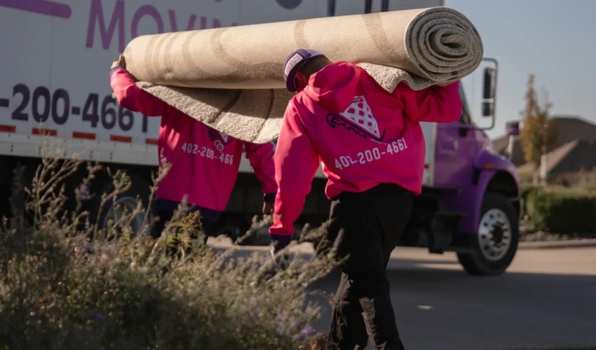 Easy as Pie Omaha movers carrying a large rolled carpet from the truck during a residential move. Local Movers Omaha