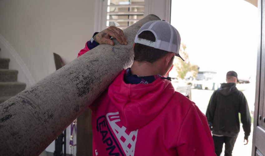Person carrying carpet roll indoors