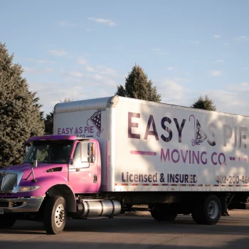 Bright pink Easy As Pie Moving Co truck helping a family moving to Omaha with family in a residential area
